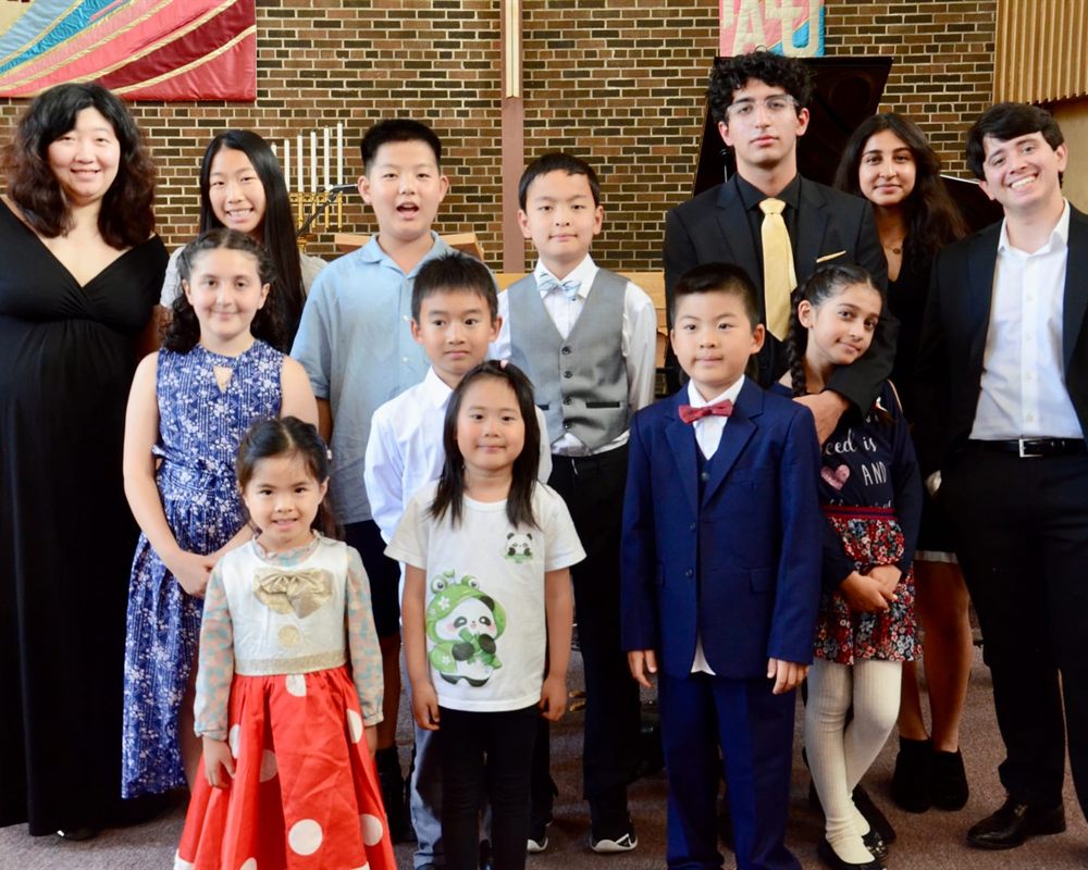 Shuman Zhou and Carlos Fernandez with eleven students in formal dress after the spring recital